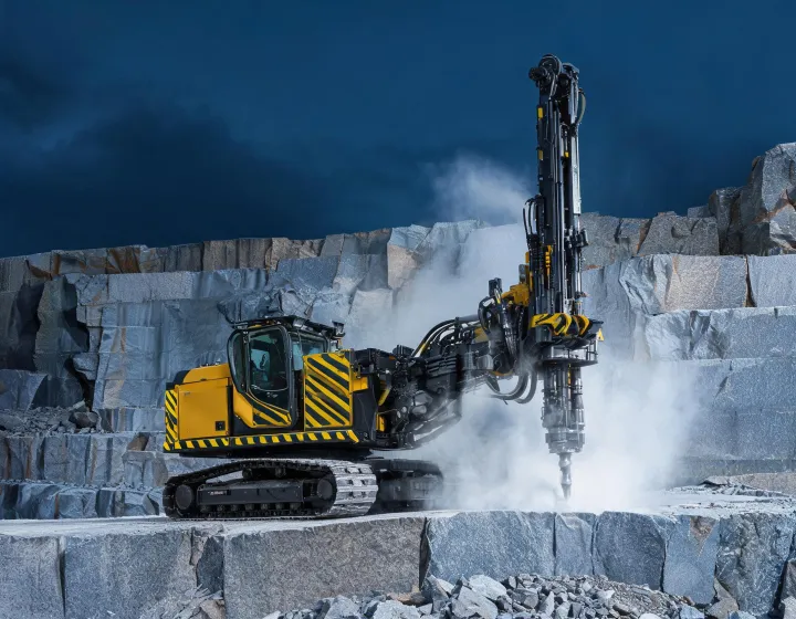 Epiroc surface drill rig boring blast holes on a quarry bench